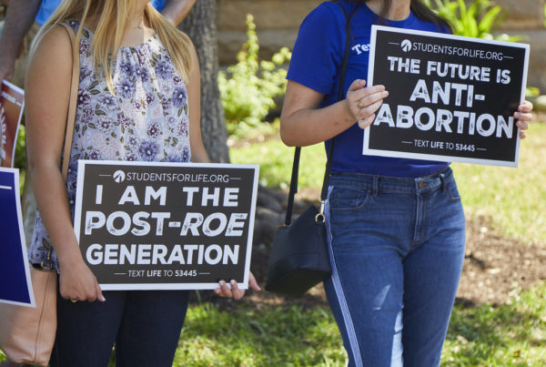 Two people hold a signs that read " I am the post-roe generation" and "The future is anti-abortion" in front of the Texas State Capitol in response to the Supreme Court's decision to overturn Roe v. Wade on June 25, 2022. Karina Lujan/KUT