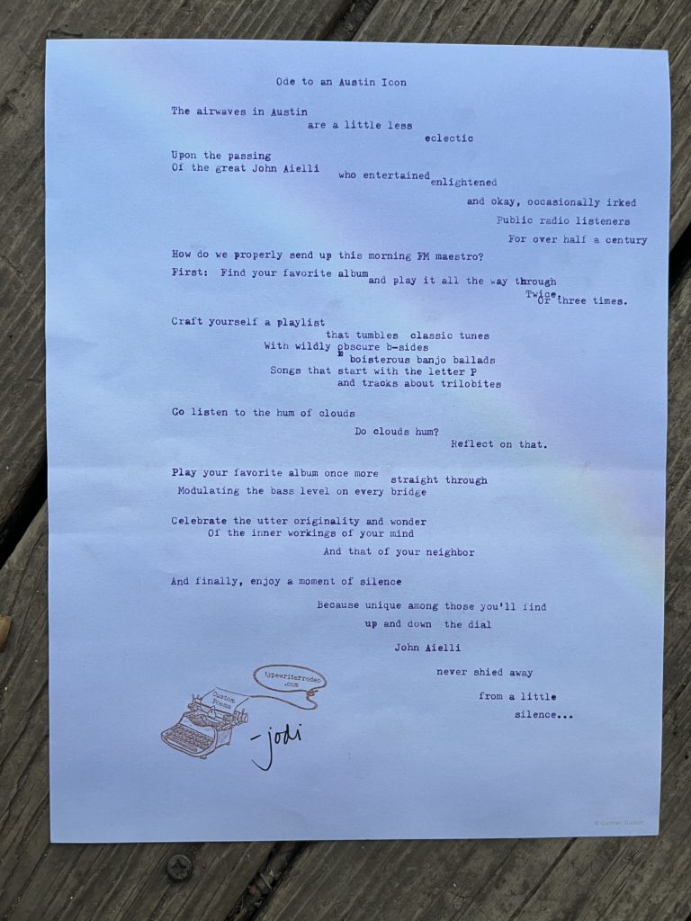 a photo of the typewritten poem on a light purple piece of paper with a rainbow running diagonally through it
