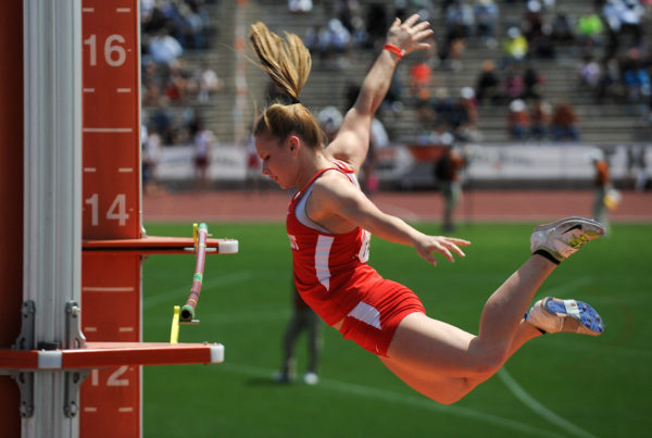 A female athlete clears the bar in a pole vaulting competition.
