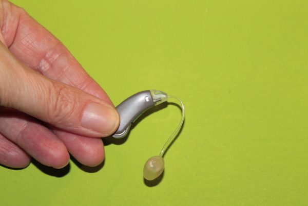 a hand holds a hearing aid