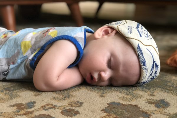 A very young child naps on a rug.