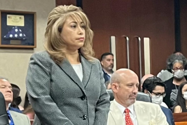 El Paso District Attorney Yvonne Rosales, standing, in a gray suit, at a hearing related to the case against the 2019 mass shooting at a local Walmart.