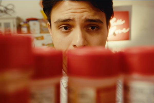 A man looks concerned as he eyes a row of identical spices in a cabinet.