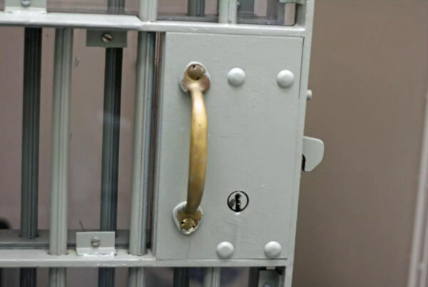 A closeup of the handle of a jail cell door is shown.