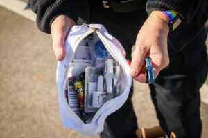 Hands holding a packet of narcan nasal sprays and other medications