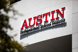 A building sign that says "Austin" in capital red letters with "Independent School District" in smaller black letters below that