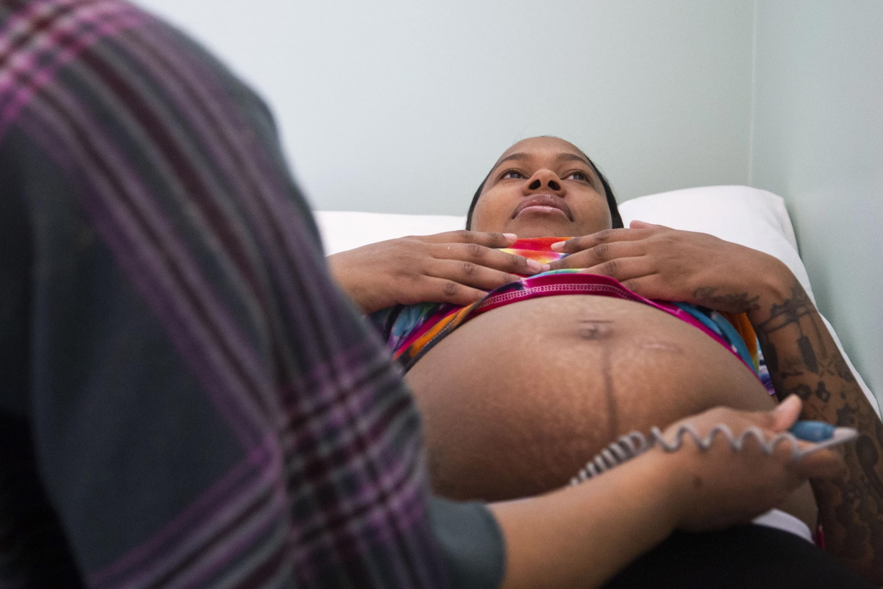 A pregnant woman is seen laying back with her stomach exposed as a nurse examines her. The woman laying back is Cherish Sims.