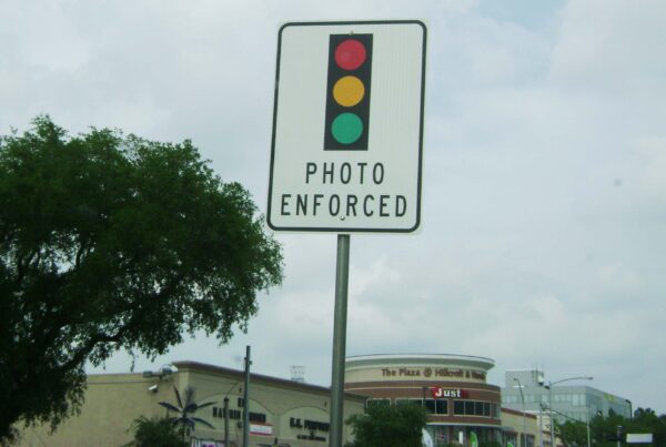 A traffic sign with a graphic of a traffic light above the words "photo enforced"