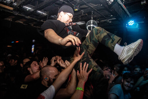 A person crowd surfs over an audiemce in a dark mnightclub