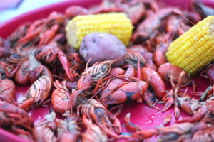 a close-up photo of a tray of boiled crawfish, red potatoes and corn on the cob