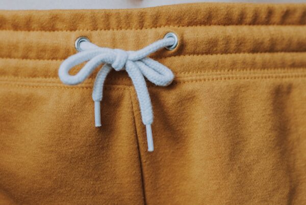 A close-up photo of the pullstring and elastic waistband of a mustard yellow pair of sweat pants.