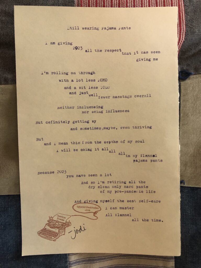 A photo of the typewritten poem on a torn piece of yellow paper. The paper is lying on a quilt