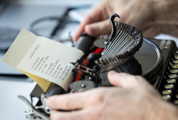 A close up photo of hands adjusting the paper reel of a vintage, manual typewriter.
