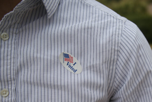 A close-up of a person's chest showing a "I Voted" sticker attached to the shirt.