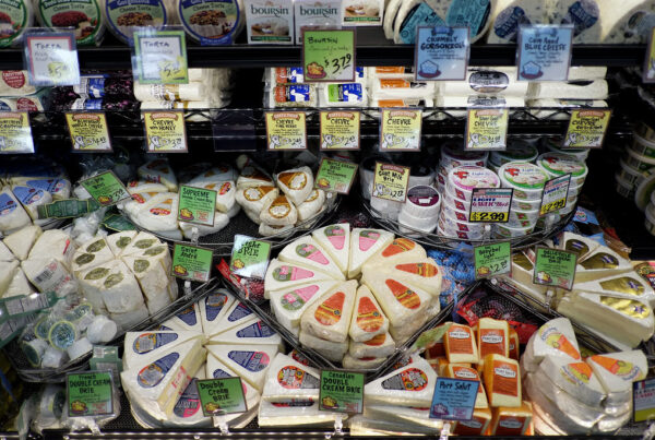 A display of assorted cheeses in a store shows many varieties.