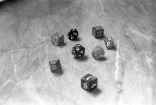 Eight dice are seen sitting on a table, with varying numbers of sides.