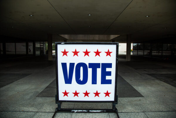 A white sign that says "VOTE" in blue letters with a row of red stars above and below