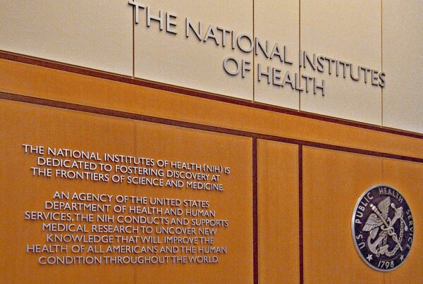 An indoor wall with lettering that says "the National Institutes of Health" and describes the agency's purpose "dedicated to fostering discovery at the frontiers of science and medicine."