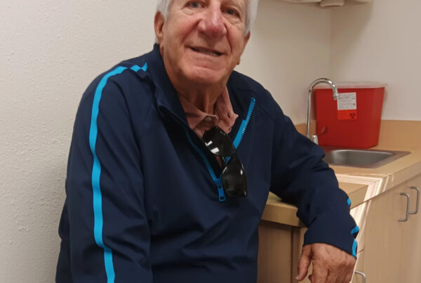An older gentlemen sits and smiles for the camera in a doctor's office. This is Dr. Alan Braid.