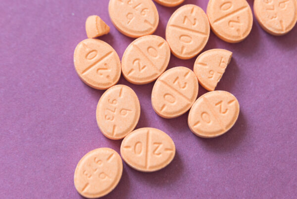 A close-up of 12 orange pills on a purple background