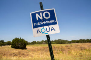 A sign is seen reading "NO Trespassing" and the logo for the water utility Aqua is seen underneath.