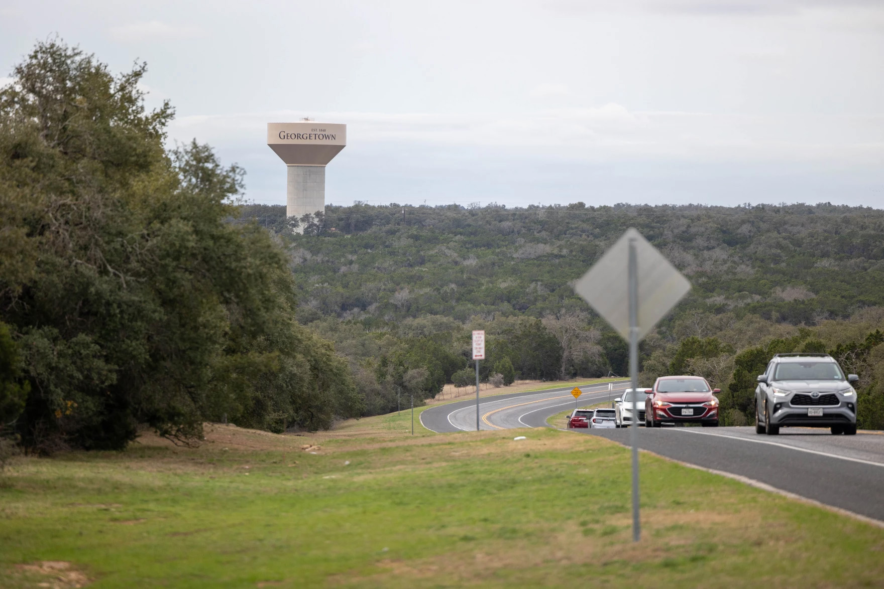 A roadway is seen with a water tower reading 
