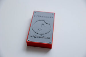 A rectangular-shaped object with a music note in the middle that says "LightSound" below the note and in Braille above it