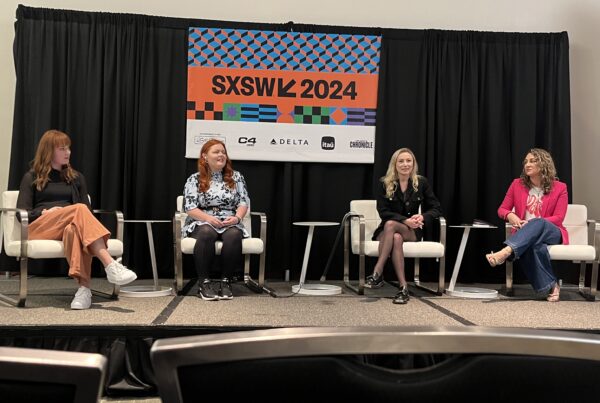 Four women seated on stage speak during a panel. The South By Southwest 2023 logo is displayed behind them.