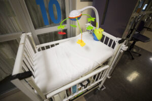 A white infant crib with a colorful mobile hanging over it