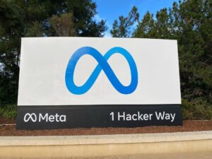 A sign with the blue Meta logo that says "Meta - 1 Hacker Way"