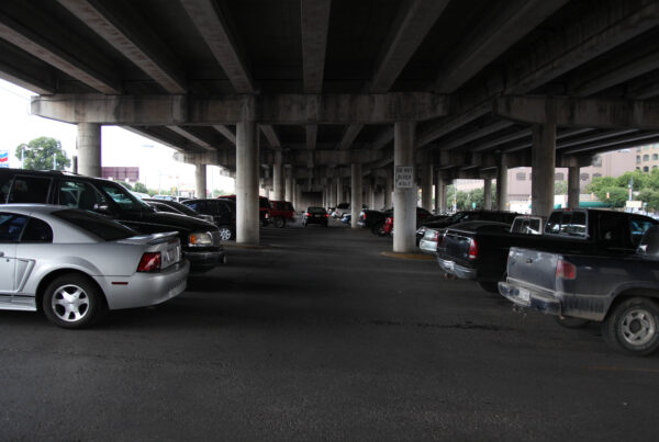 Cars in a parking lot under a highway