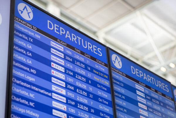An electronic screen lists flight departure times