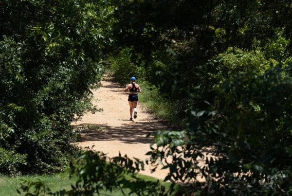 A woman runs outside on a trail lined with trees