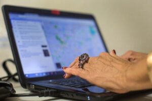 A woman's hands are seen typing on a laptop computer.
